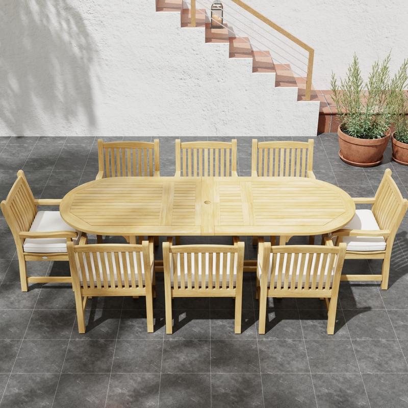 alt="70178 Montserrat Veranda Teak 9 pc Dining Set of Montserrat Dining Table and 8 Veranda Side Chairs in angled side view on outdoor patio with potted plant and staircase of house in the background"