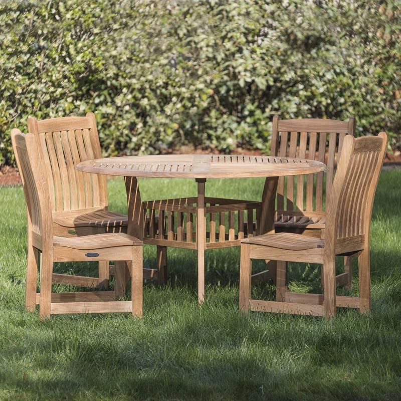 alt="70040 Veranda Hyatt 5 piece teak Dining Set of 4 side chairs and 48 inch round dining table on grass lawn with concrete walkway and mulched landscaped area in background"