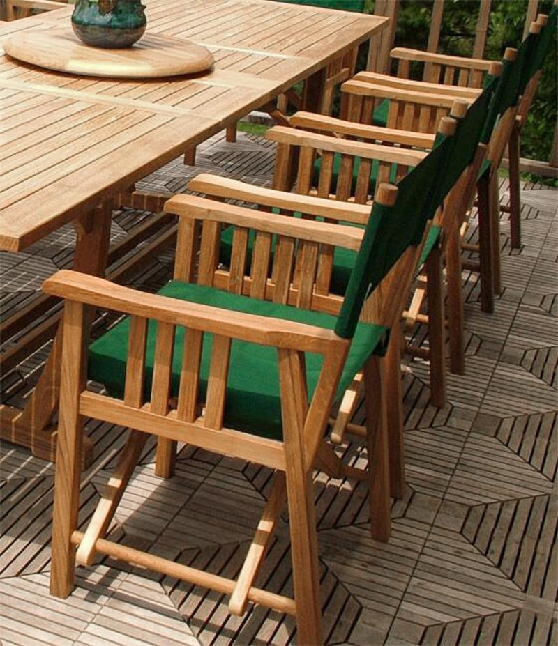 alt="70006 Veranda teak 11 piece dining set close angled view of director chairs plant on teak lazy susan on teak floor deck with trees in background"