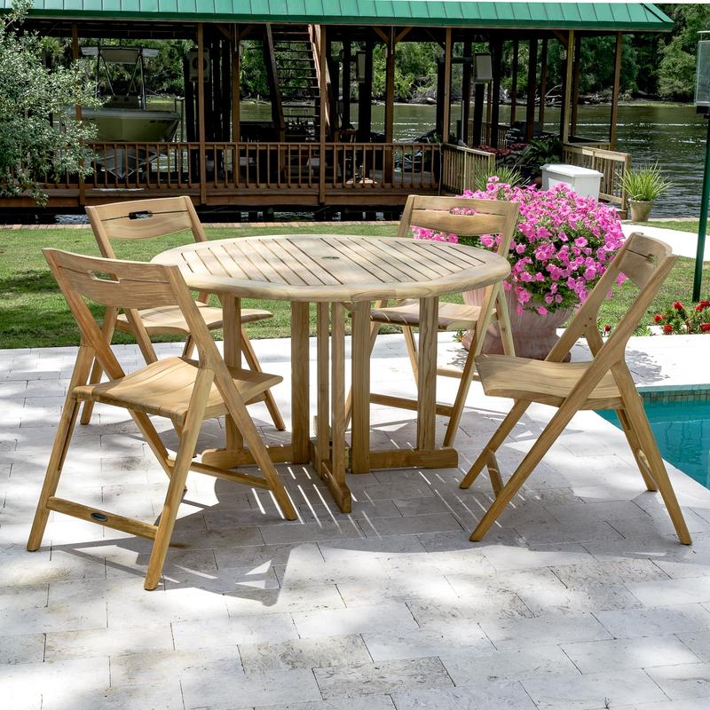 alt="70474 Surf Barbuda Folding Dining Set of 4 folding side chairs and round 48 inch diameter table on pool deck with potted flowering plants a gazebo and lake in background"